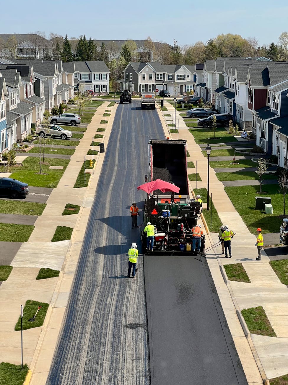 Workers repaving a residential street in a suburban neighborhood.