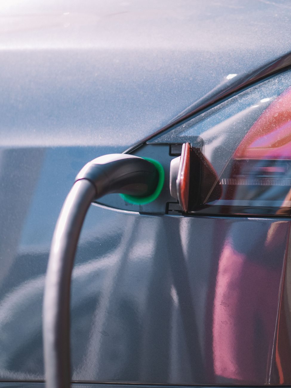 An electric vehicle plugged into a charging station outdoors.