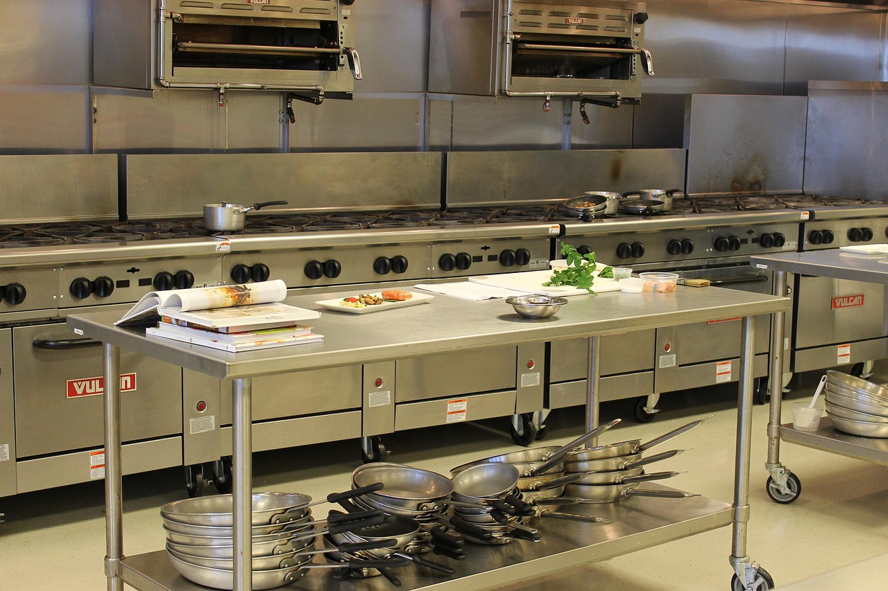 Commercial kitchen with stainless-steel food-preparation equipment and work surfaces.