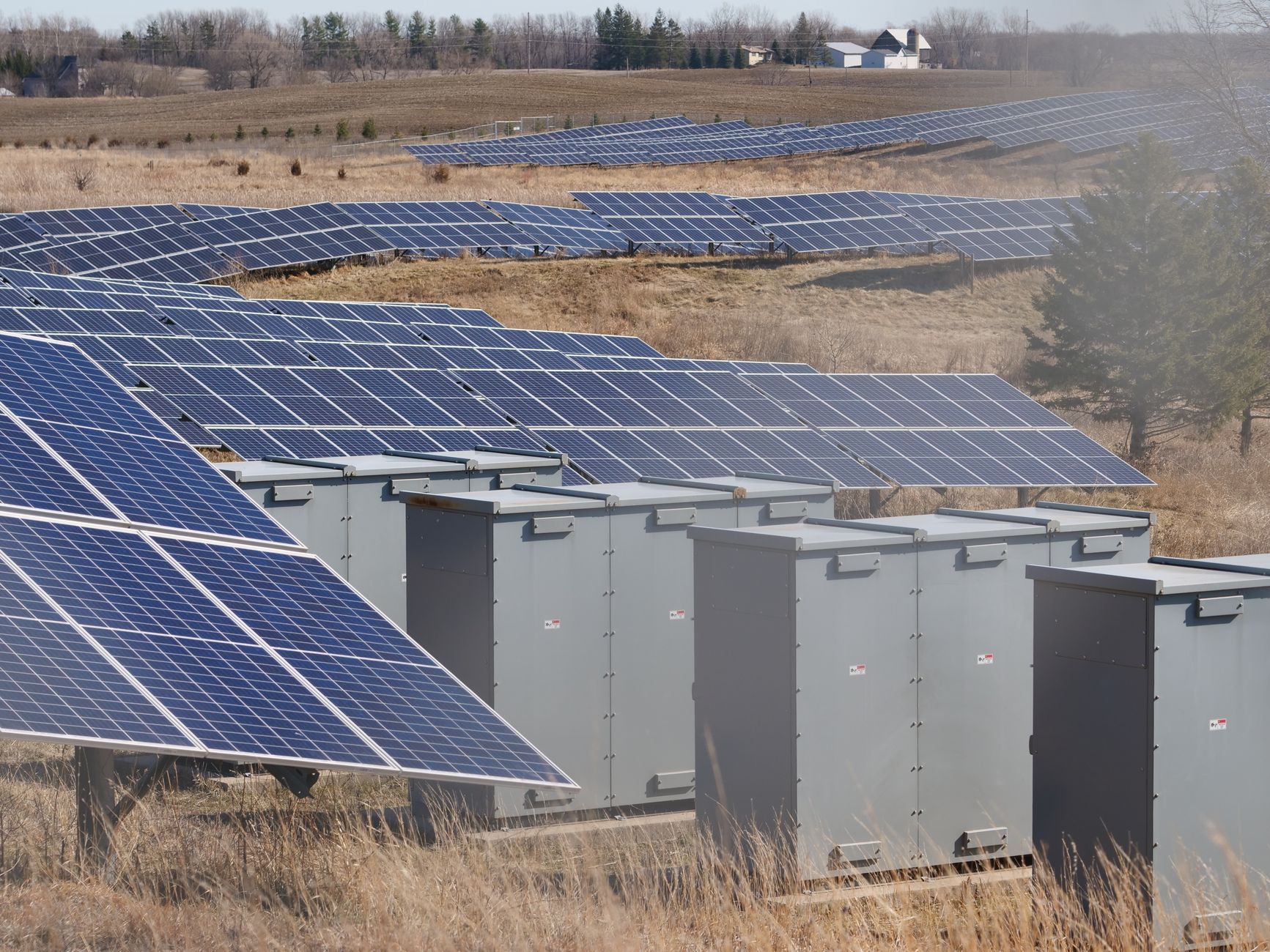 Image of rows of solar panels in a rural landscape.
