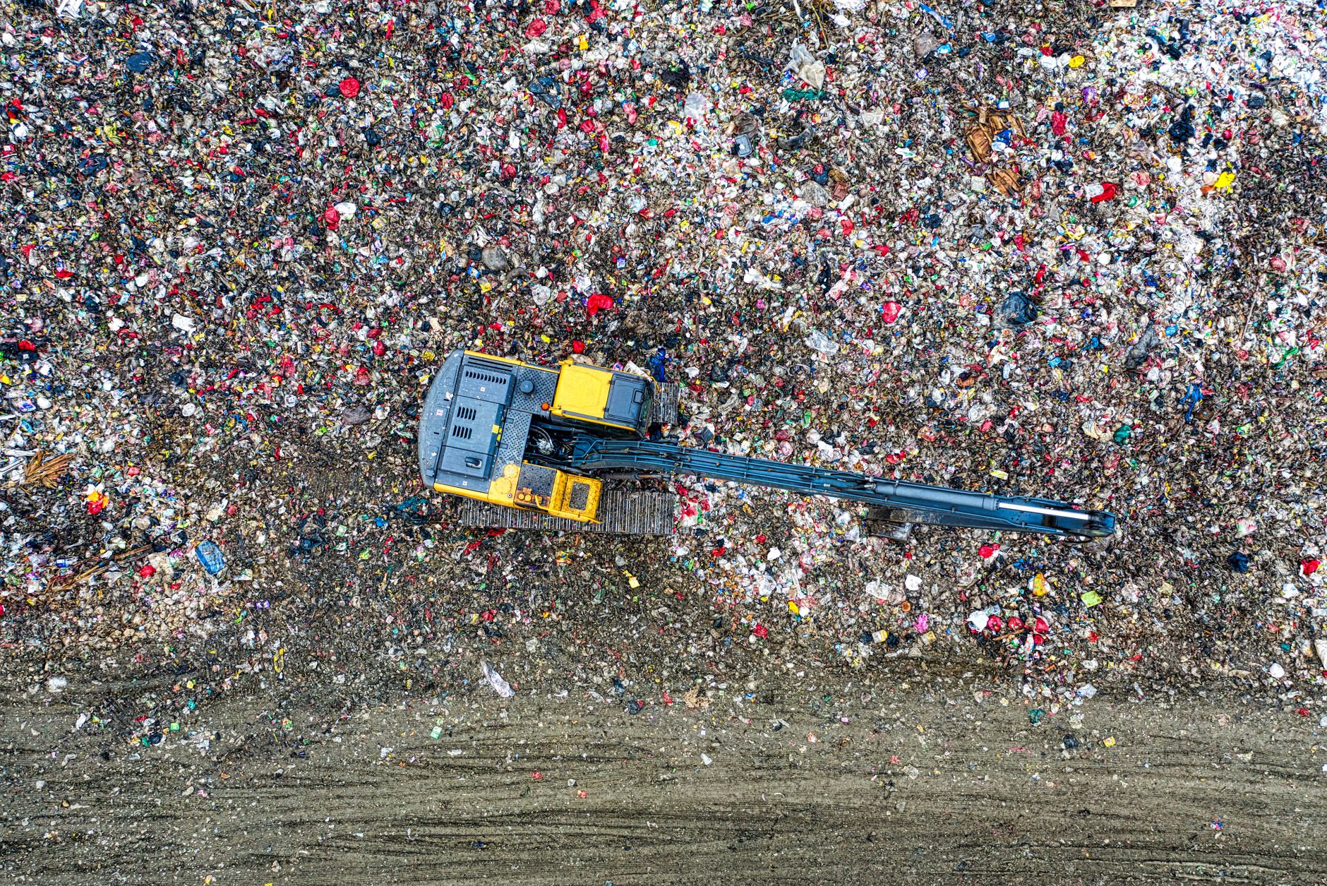 An excavator works at a large waste-disposal site.