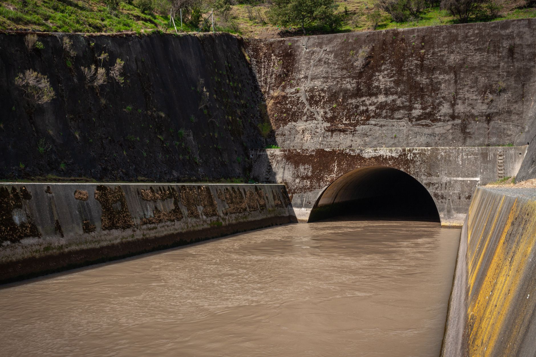 Concrete storm drain tunnel with water flowing through it.