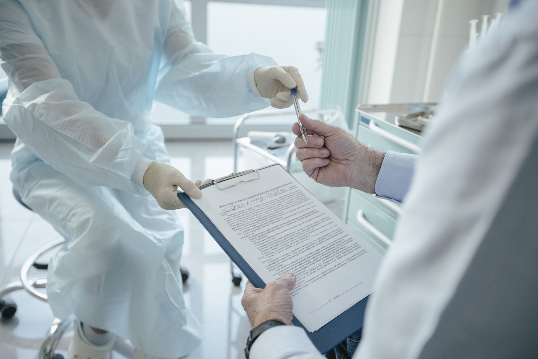 A doctor hands a clipboard to a patient in a medical office.