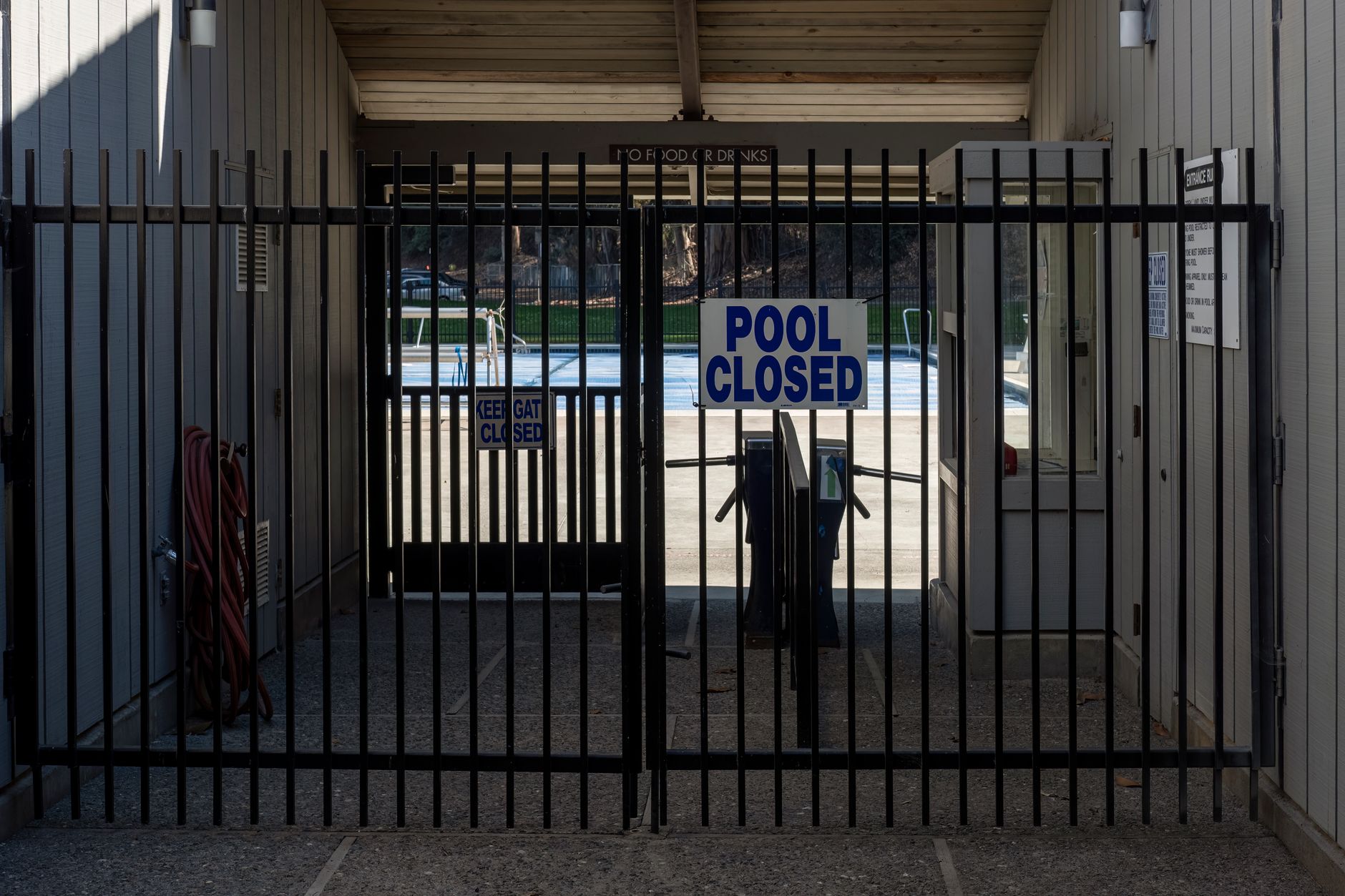 A gate blocks the entrance to a closed community swimming pool.