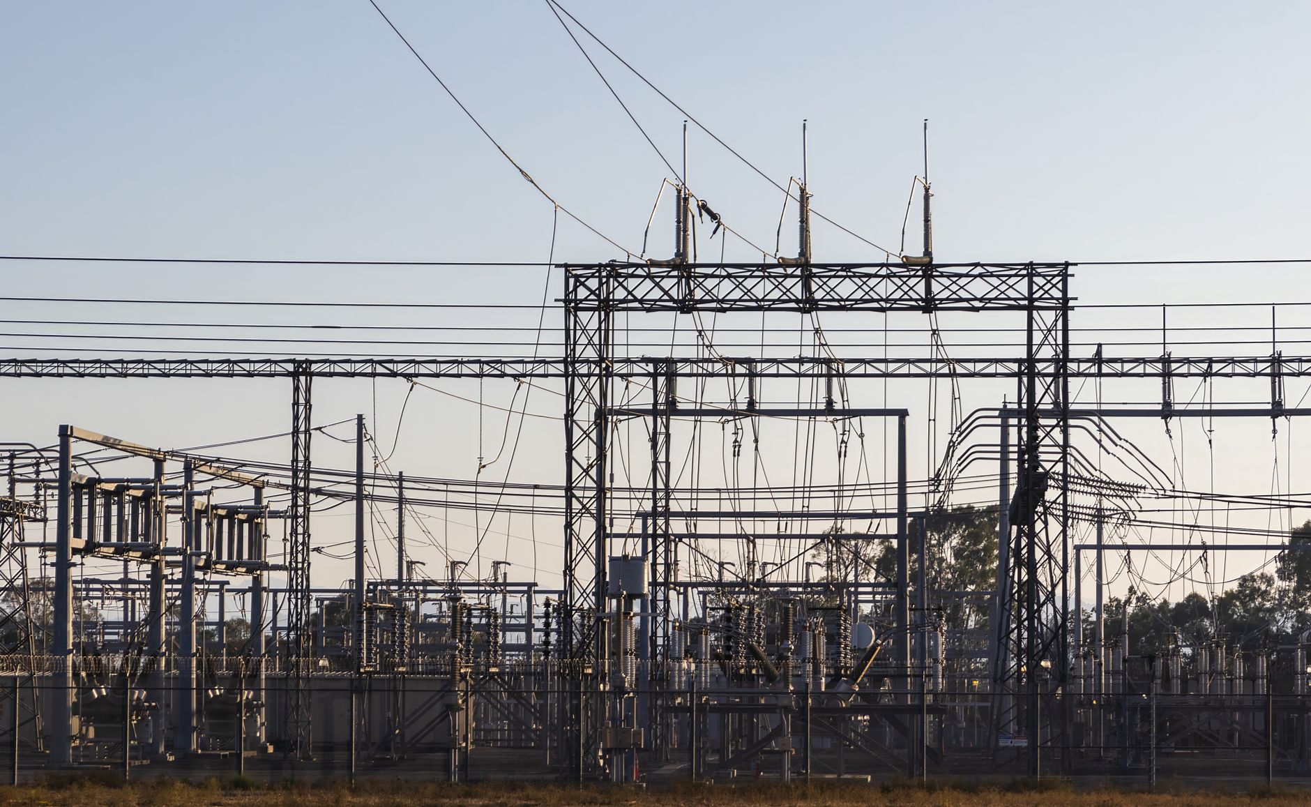 High-voltage substation equipment and power lines are silhouetted against the sky.