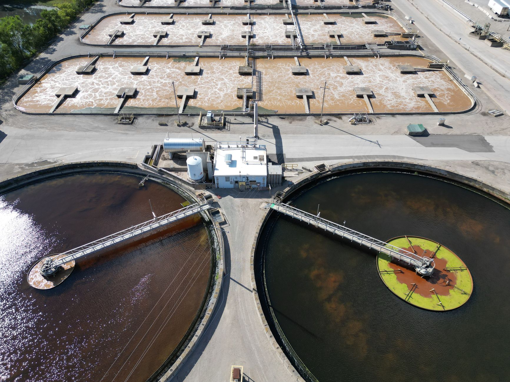 Aerial view of a wastewater-treatment plant with large circular treatment tanks.