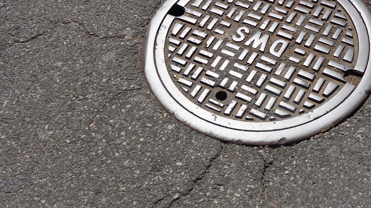A storm manhole cover set in an asphalt street.